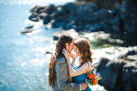 Couple on rocks with ocean in front of them.