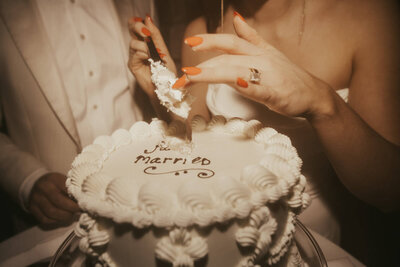 Bride and groom cut the cake that reads 'just married' in icing